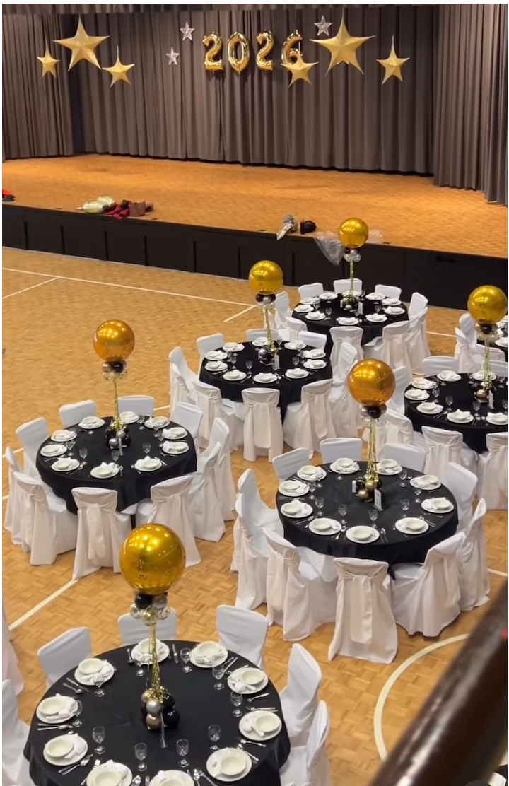 Decorated event space with tables, chairs, and balloons in a large hall.